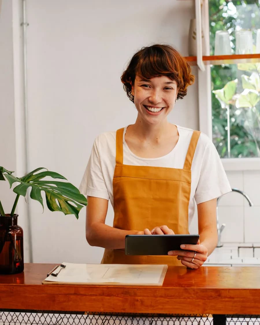 Junge Unternehmerin mit Tablet an der Ladentheke – Homepage erstellen lassen für kleine Unternehmen