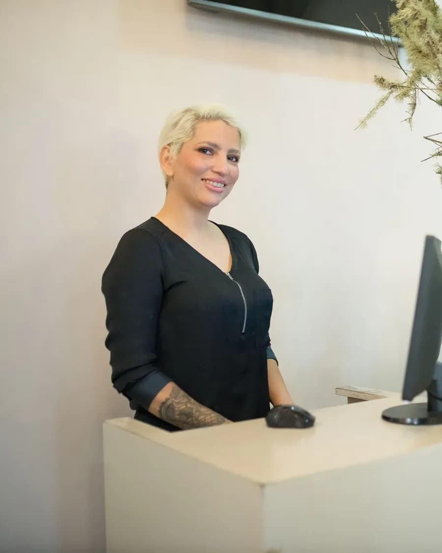 Salon-Inhaberin steht lächelnd am Empfangstresen – Website mit Online-Terminbuchung erstellen lassen