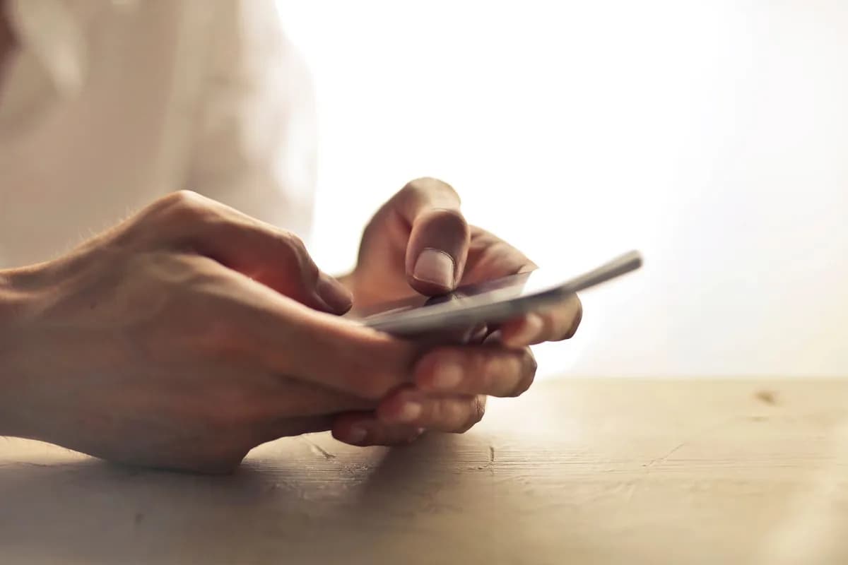 Hände halten ein Smartphone im Gegenlicht – Website für Smartphones optimiert